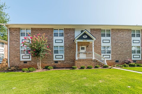 a brick apartment building with a green lawn in front of it